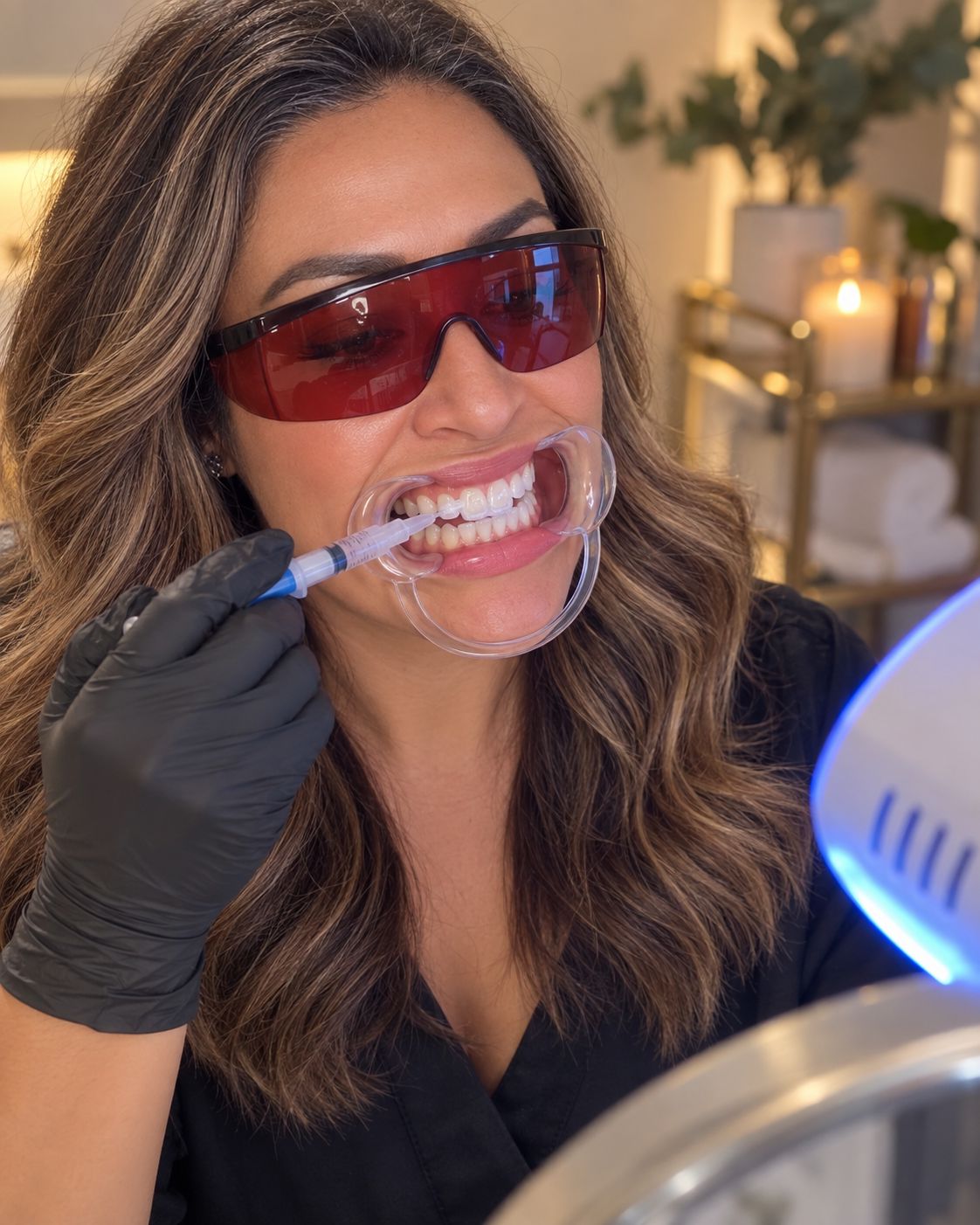 Bright Now technician applying whitening gel to a smiling guest's teeth with a cheek retractor during a Prescott, AZ teeth whitening session